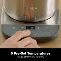 Ninja kitchen appliance with digital control panel and hand adjusting settings on a wooden surface.