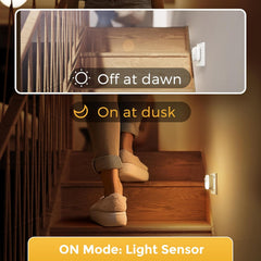 Person ascending wooden stairs with light sensor switch labeled 'On at dusk' and 'Off at dawn'.