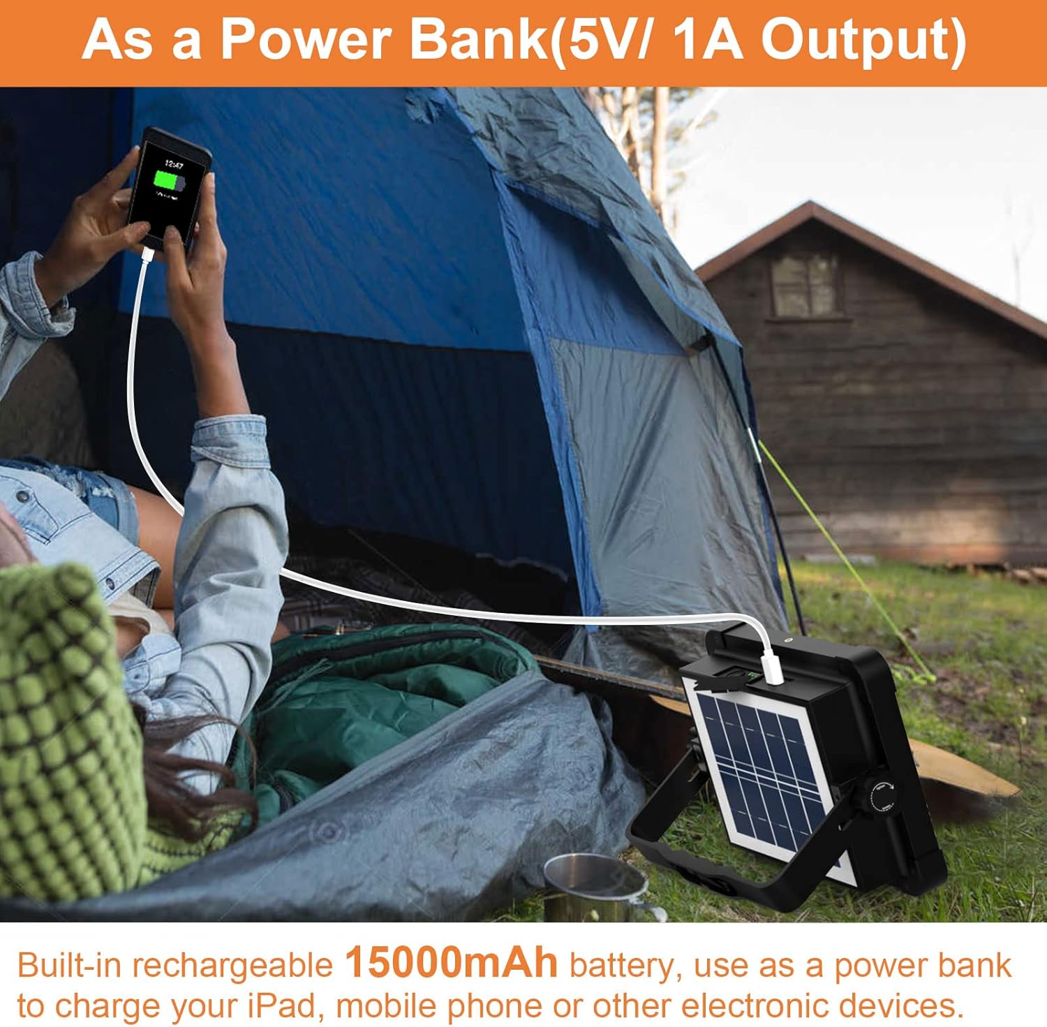 Person camping with a solar panel and power bank, charging electronic devices outdoors.
