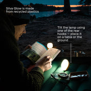Person reading a book with Silva Glow lamp on a beach at night