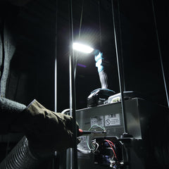 Person using a flashlight to inspect equipment in a dark setting