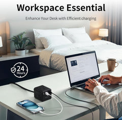 Person using a laptop at a desk with a power adapter and phone, bedroom in the background