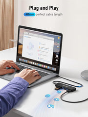 Person using a laptop with a USB hub on a desk, emphasizing 'Plug and Play' feature.