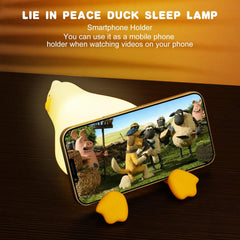 Smartphone holder with duck-shaped lamp displaying a cartoon scene on a phone screen.