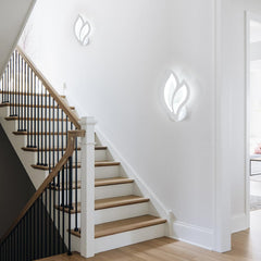 Staircase with wooden steps and black railings against a white wall with modern wall lights.