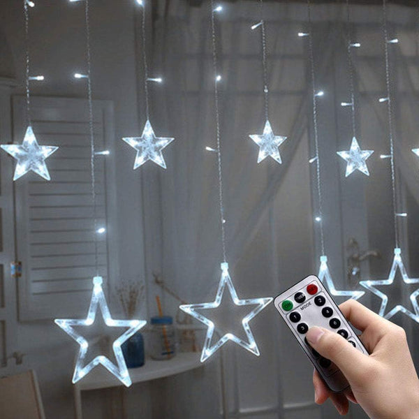 Star-shaped LED string lights with a remote control in a room setting.