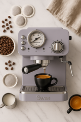 Swan espresso machine with coffee beans, a bowl of coffee, and a cup on a marble surface.