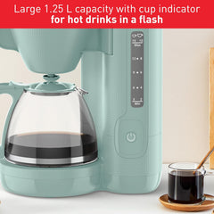 Teal coffee maker with glass carafe and cup of coffee on a white surface.