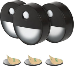 Three black motion sensor lights with adhesive pads on a white background
