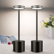 Two black floor lamps on a light-colored surface with flowers and a magazine in the background.