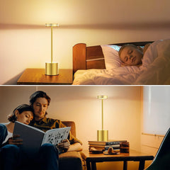 Two people reading a book together with a lamp on a table between them.
