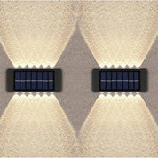 Two solar-powered wall lights on a textured wall.