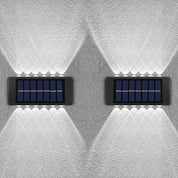 Two solar panels mounted on a textured white wall.