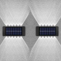 Two solar panels mounted on a textured white wall.