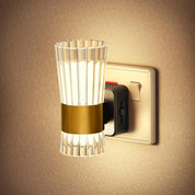 Wall-mounted light fixture with glass shade and gold accent on a beige wall.