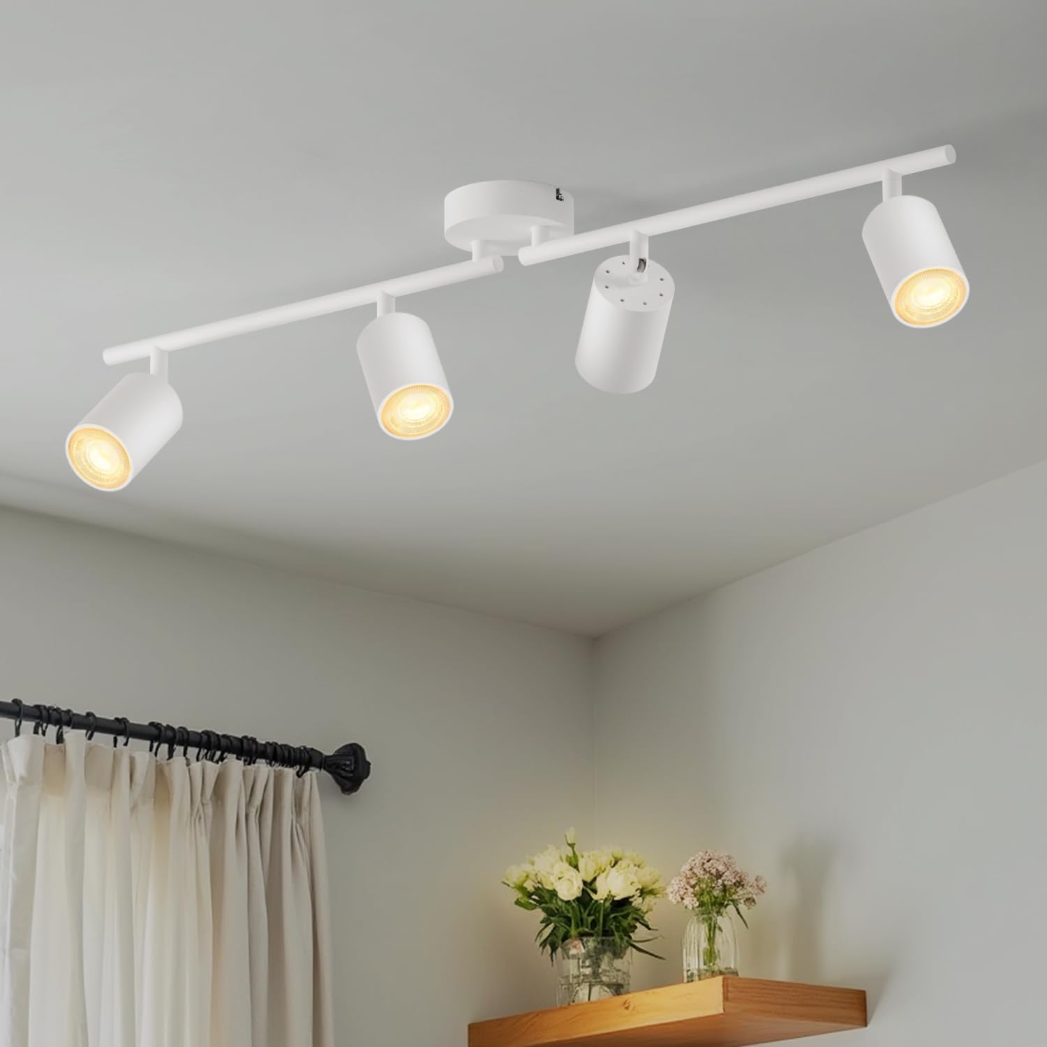 White ceiling track lights on a gray ceiling with a shelf and flowers in the foreground.