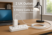 White power strip with two UK outlets on a desk, connected to a laptop and lamp, with text about cable length and outlet capacity.