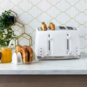White toaster with slices of bread on a kitchen counter, next to a jar of honey and a plant.