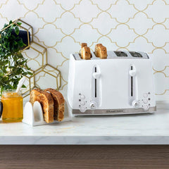 White toaster with slices of bread on a kitchen counter, next to a jar of honey and a plant.