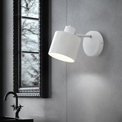 White wall-mounted lamp on a gray wall with a window in the background