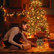 Woman opening a gift in a cozy living room decorated for Christmas.