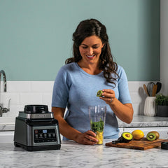 Woman preparing a smoothie with a blender in a kitchen