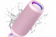 Pink Bluetooth speaker with water splashes on a white background